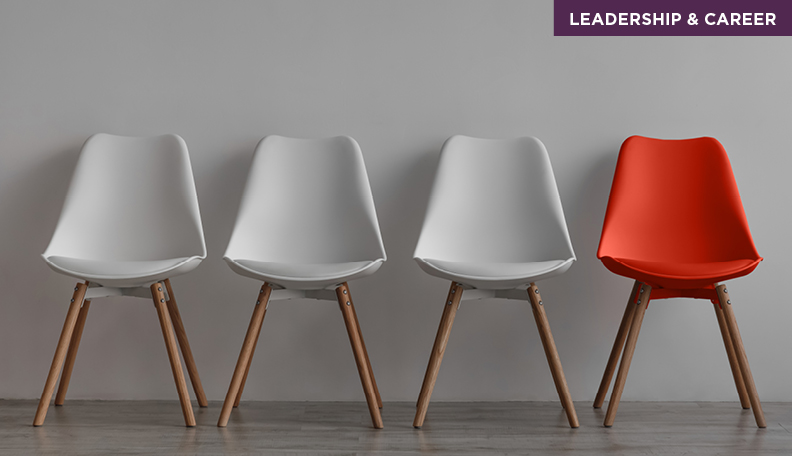 Chairs in a row, all grey apart from one in red