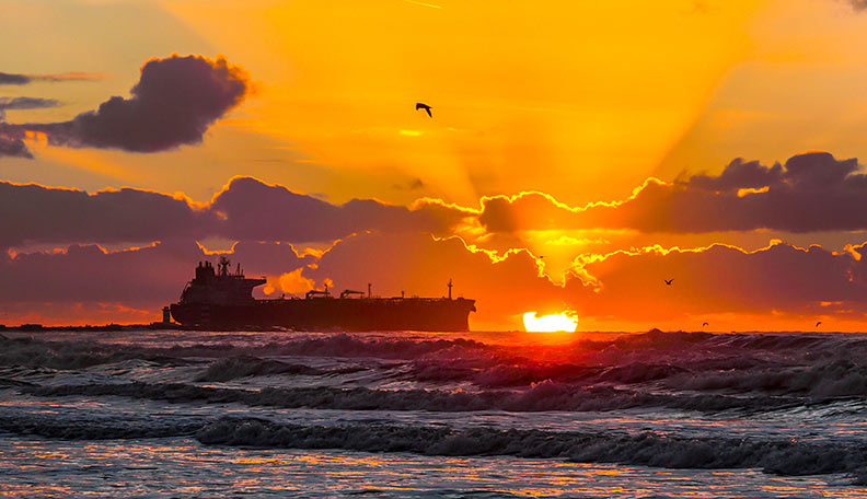 Image of a large cargo ship at sea, at sunset