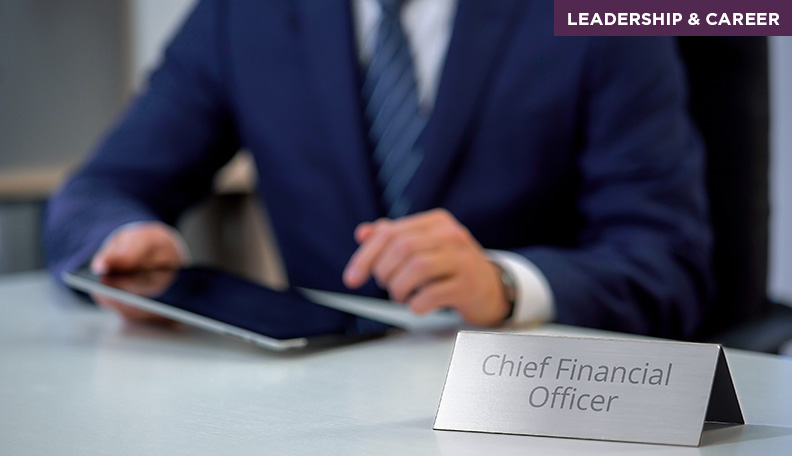 Image of a man in a suit sitting at a desk with the sign ‘Chief Financial Officer’