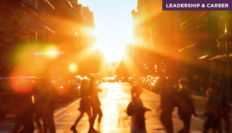 Image of a city street with a setting (or rising) sun shining through buildings