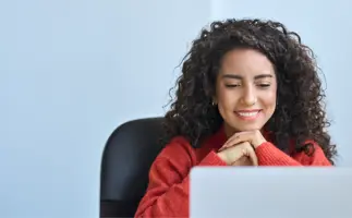 Woman smiling at her laptop, online learning 